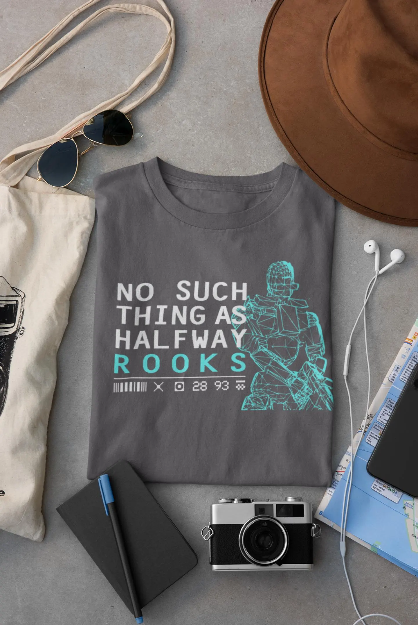 Gray t-shirt with graphic design and text, surrounded by accessories on a gray surface