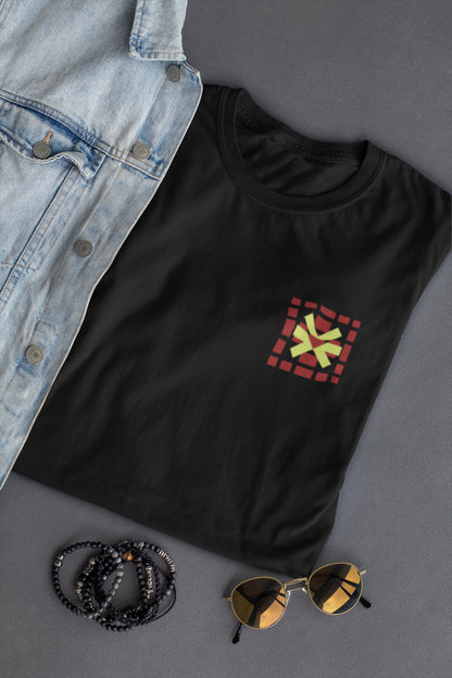 Black t-shirt with a colorful square design, denim jacket, sunglasses, and beads on a gray surface.